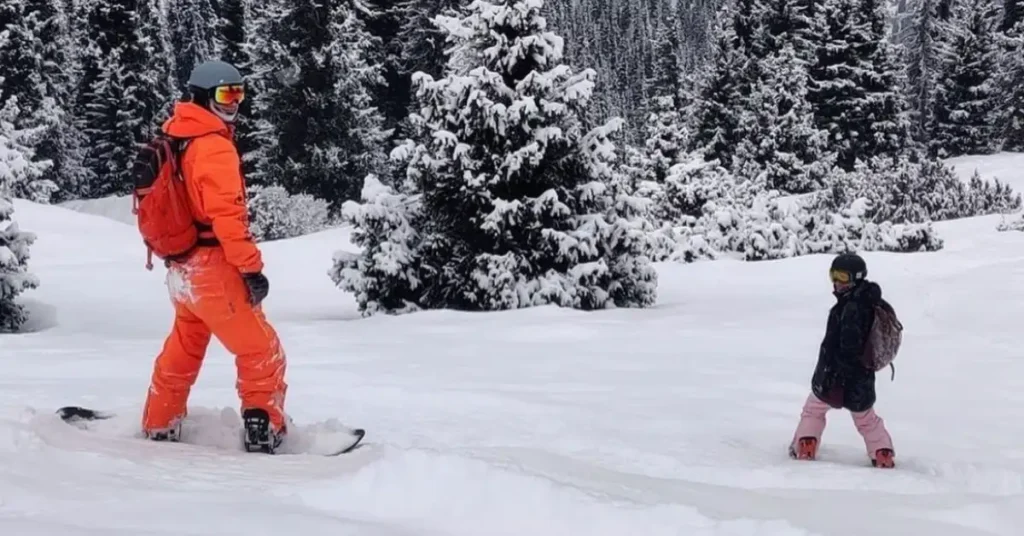 orange dressed man and black dressed woman snowboarding