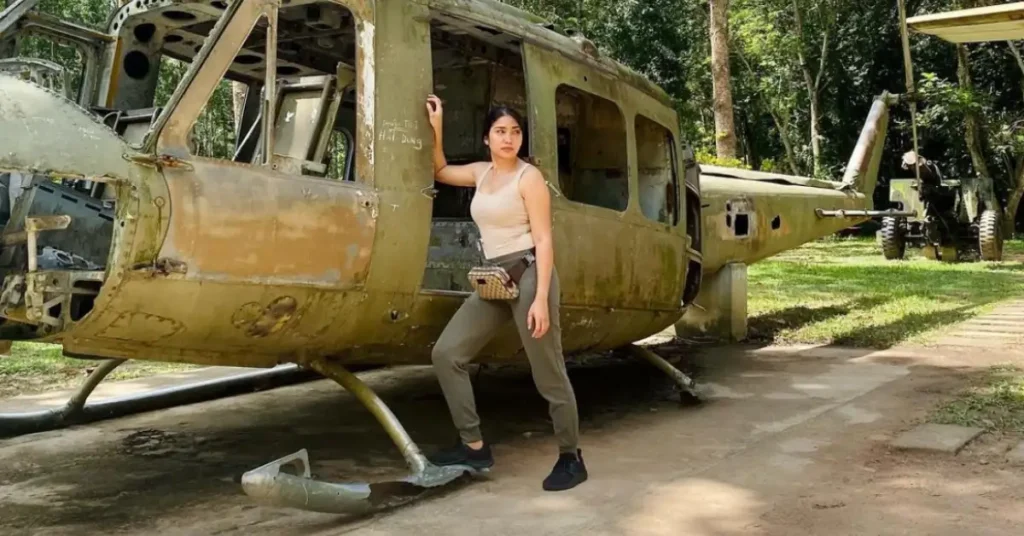 young woman standing at an old helicopter