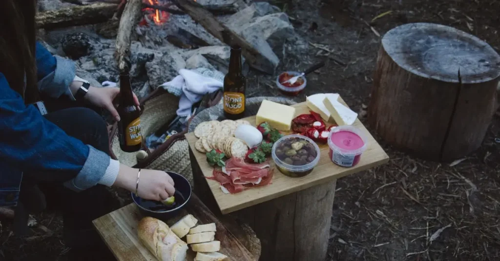 woman camping outside cooking and drinking beer