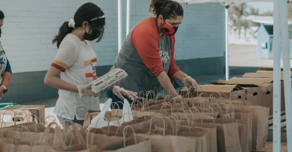 two woman packing things in paper bags